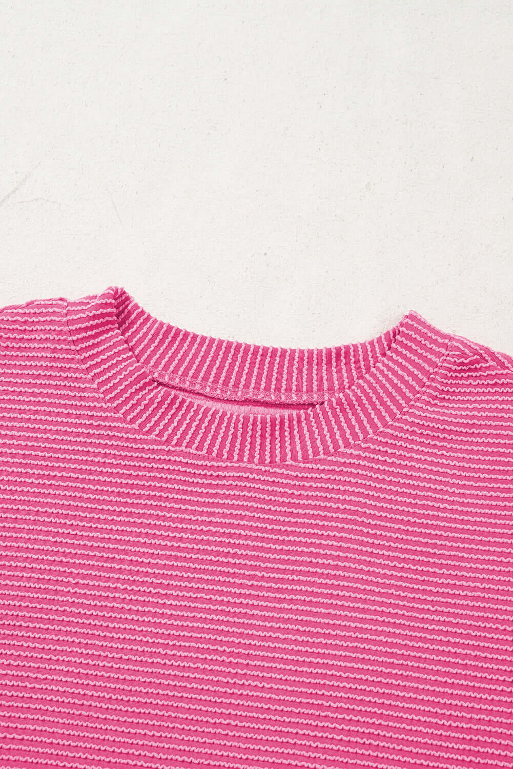 Close-up of a mock neckline in a hot pink corded knit top with textured stripes.