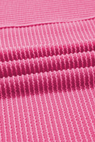 Close-up of textured corded knit fabric in vibrant hot pink color, showcasing unique dimensional stripes.