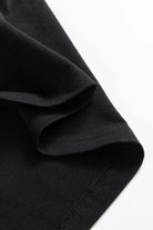 Close-up of black T-shirt fabric with visible stitching detail, showcasing quality material and craftsmanship.