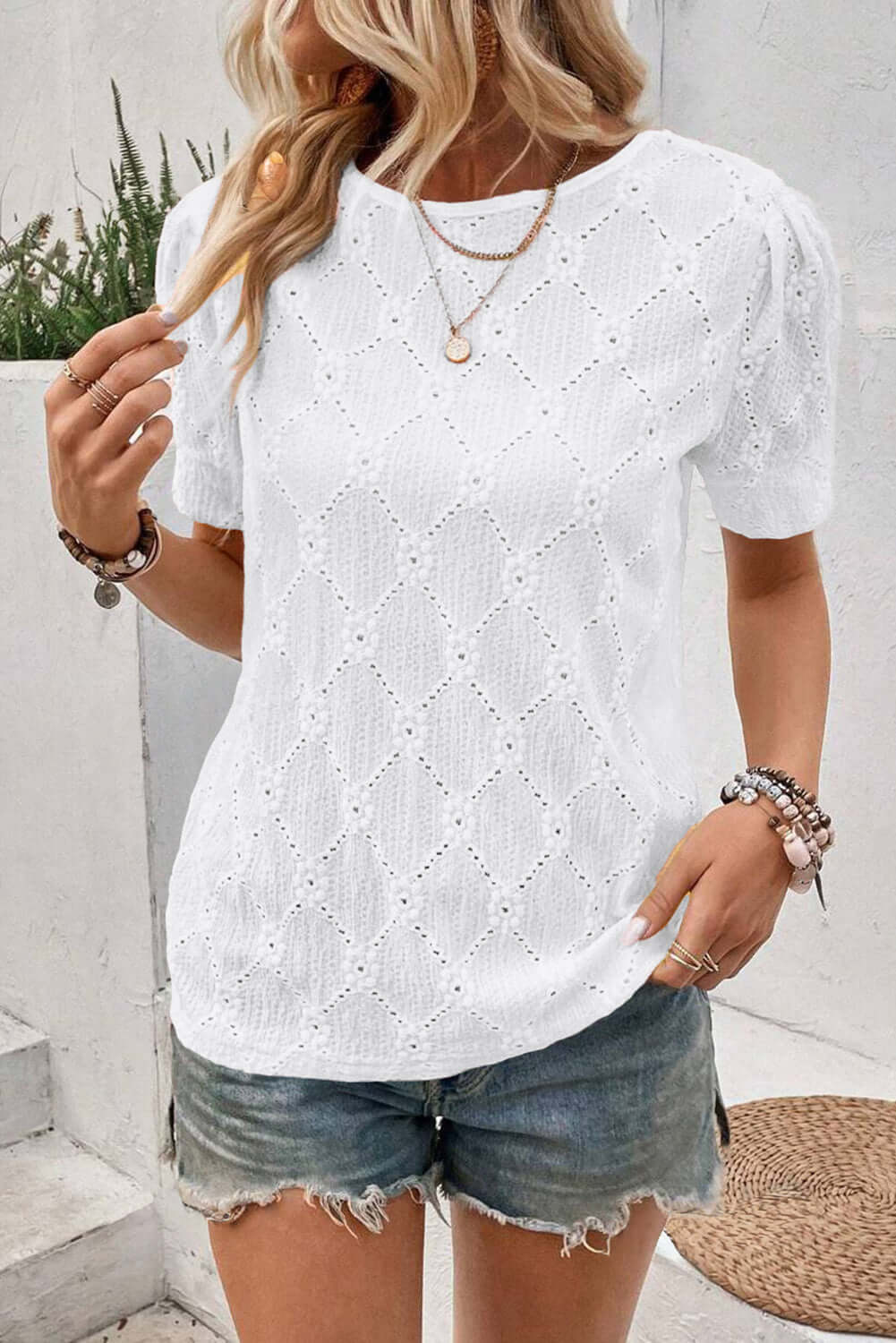 Chic white lattice and lace top with floral texture, paired with denim shorts, perfect for casual summer wear.
