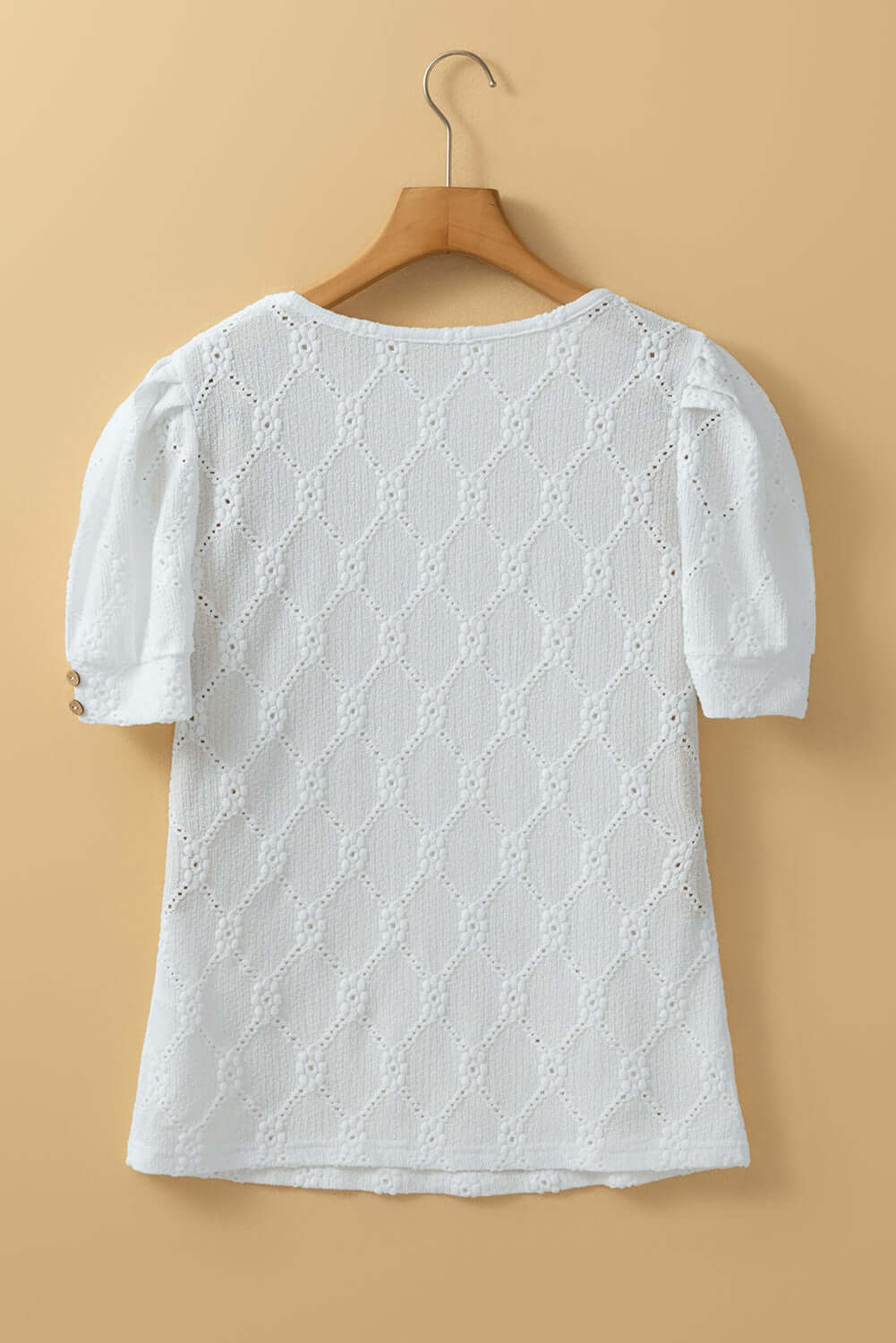 Back view of white textured floral geometric Lattice & Lace top on a hanger, showcasing chic puff sleeves.