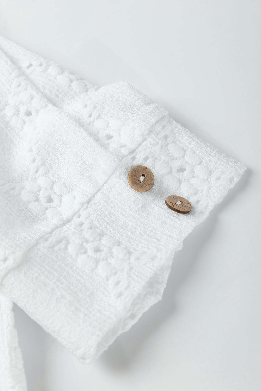Close-up of white Lattice & Lace top showcasing delicate floral texture and buttoned sleeve cuffs.