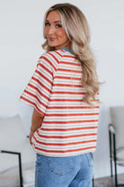 Woman showing the back of a tomato red striped Americana Mood Top with a blue collar, perfect for summer.