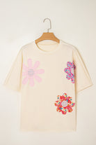 Vanilla cream top with colorful floral patches and exposed stitching for a relaxed, boutique style.