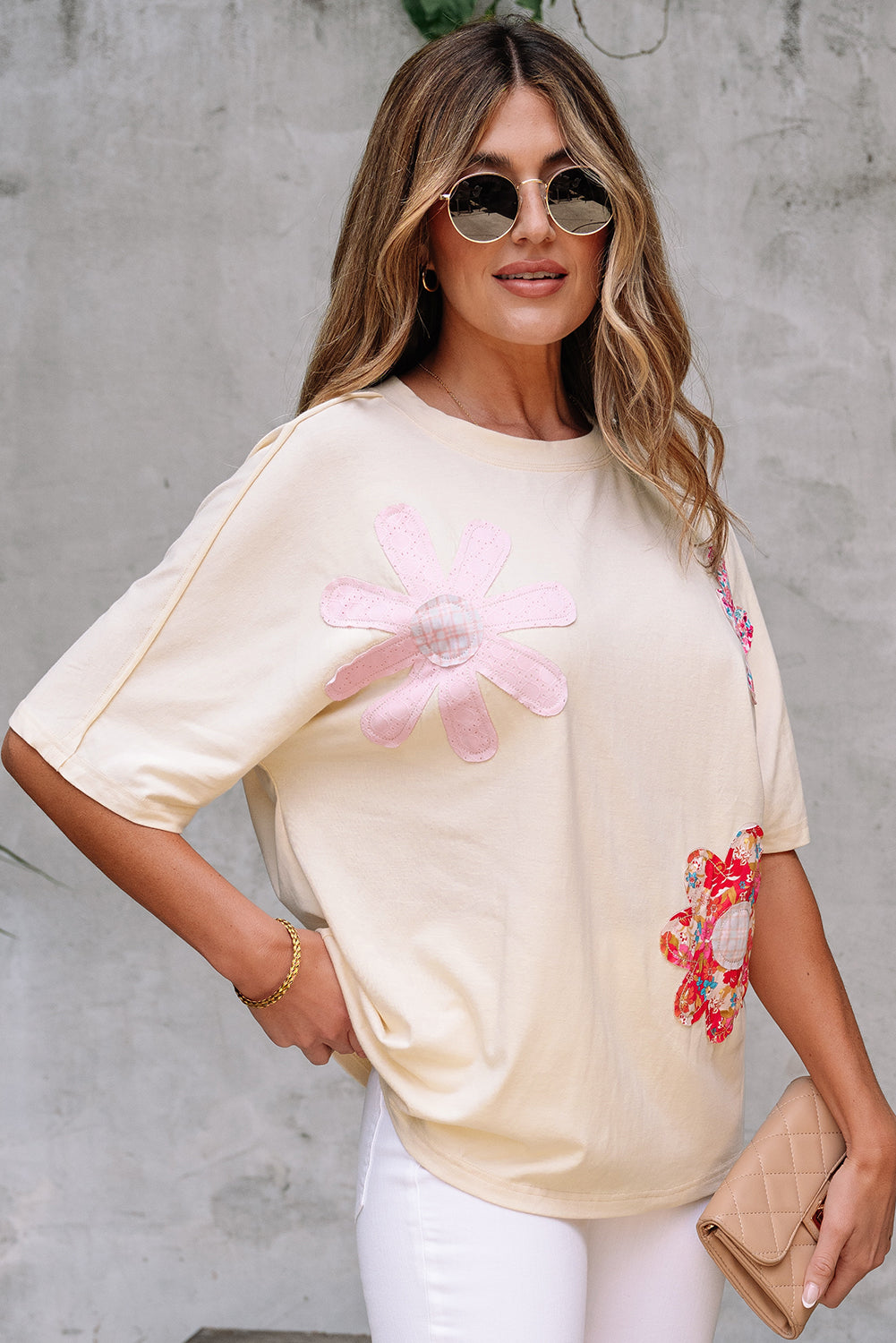 Model wearing Happiness Blooms Top in vanilla with colorful floral patches and exposed stitching.