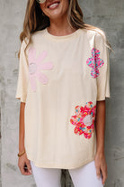 Vanilla cream top with playful floral patches and exposed stitching for a relaxed, artsy look.