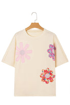 Vanilla tee with colorful floral patches and exposed stitching for a relaxed, stylish look.