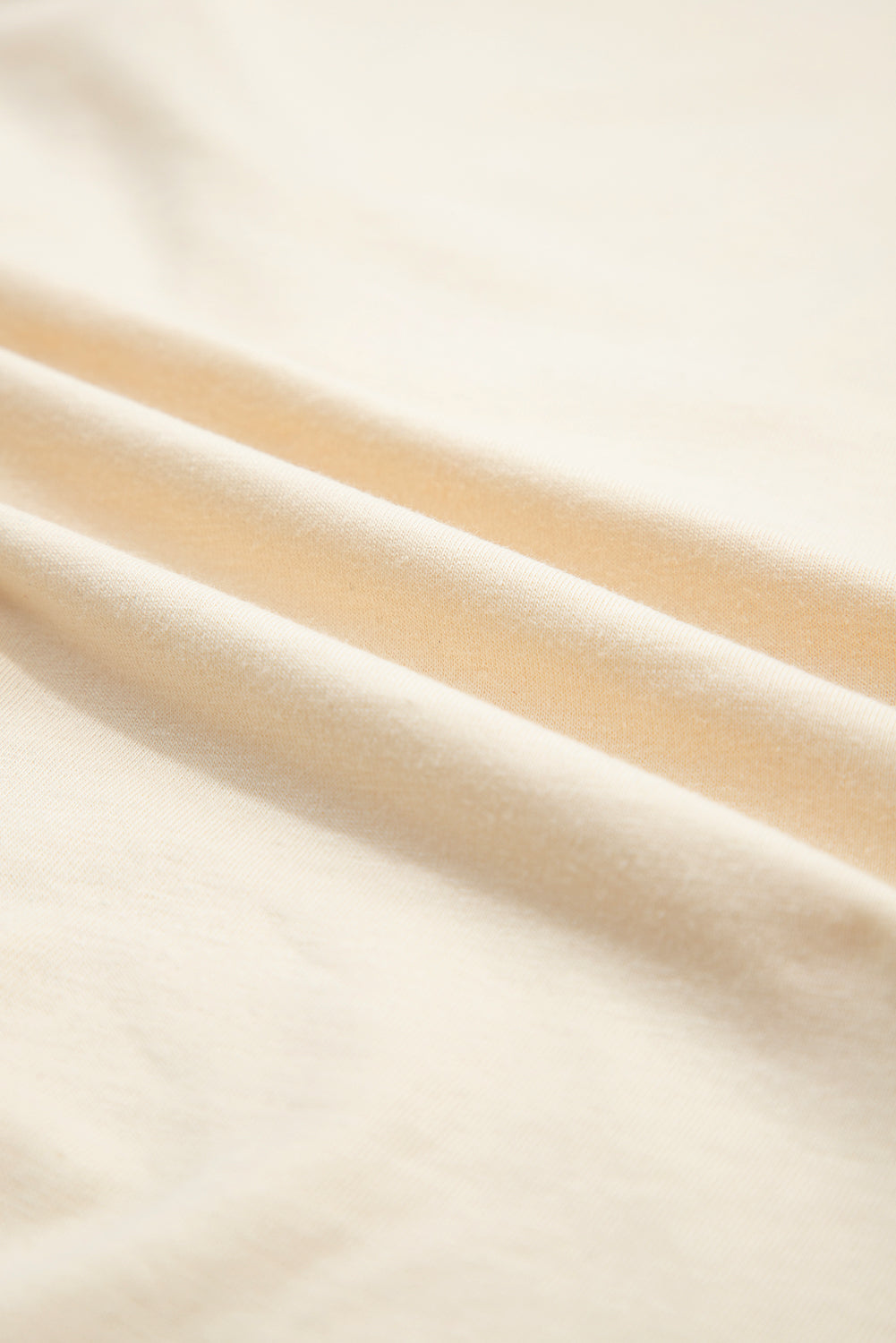 Close-up of soft vanilla cream fabric showcasing smooth texture and gentle folds.