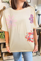 Vanilla cream tee featuring colorful floral patches and relaxed fit for a stylish, artsy look.