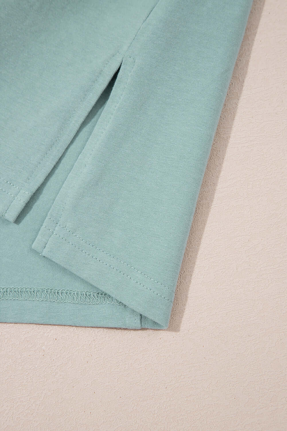 Close-up of the sage Cosmic Crush Top, featuring frayed details and relaxed sides for a trendy street-style look.