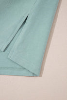 Close-up of the sage Cosmic Crush Top, featuring frayed details and relaxed sides for a trendy street-style look.