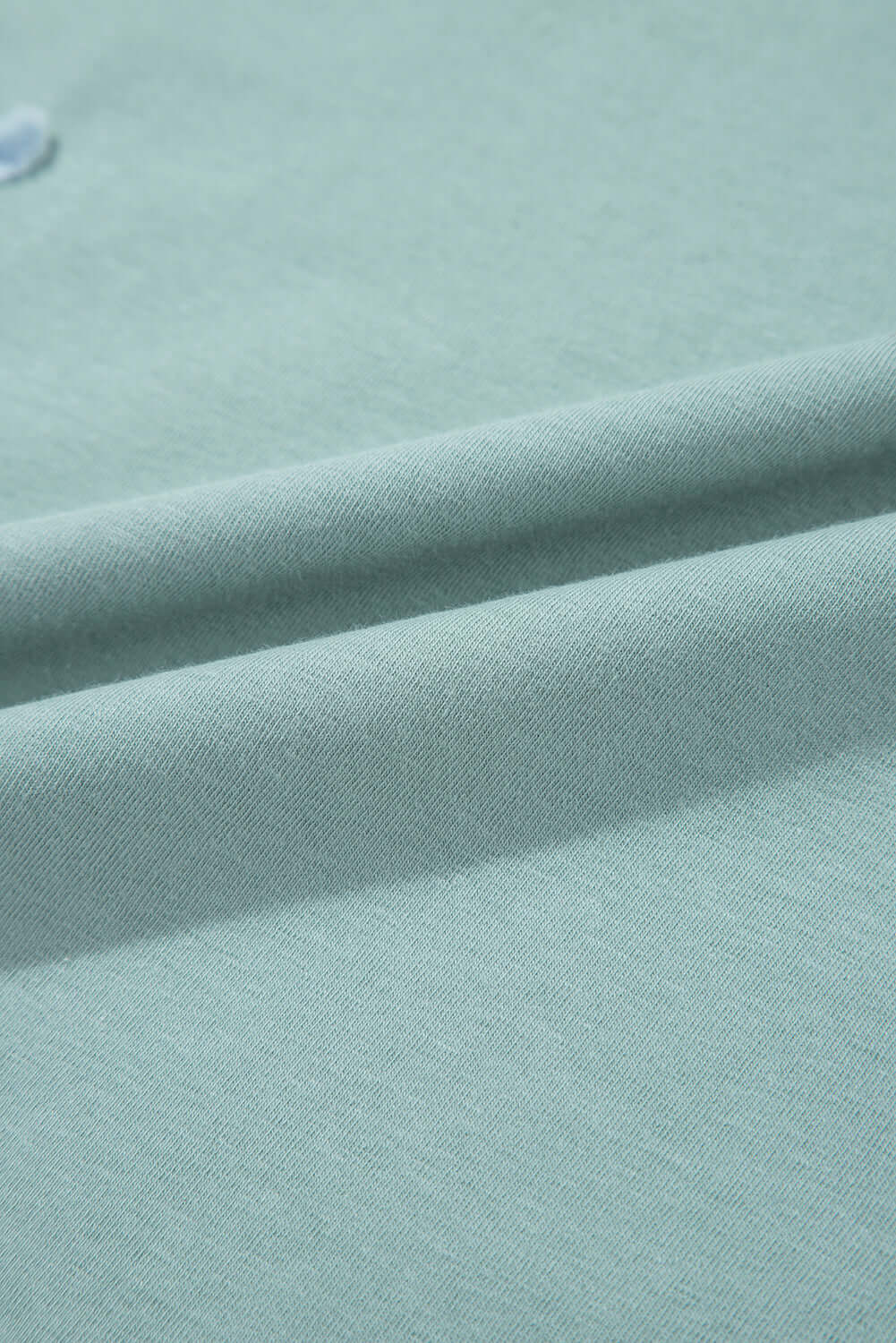Close-up of soft sage fabric showcasing smooth texture and subtle folds for the Cosmic Crush Top.