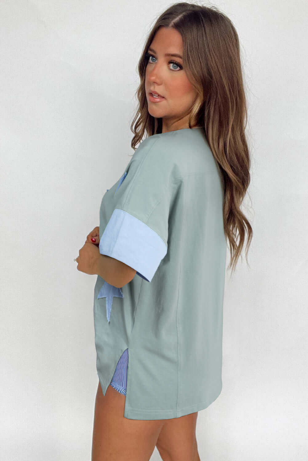 Oversized sage top with sky blue star patch and frayed details, showcasing a relaxed fit and stylish design.