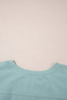 Close-up of the neckline of the sage Cosmic Crush Top, showcasing its soft fabric and relaxed fit.