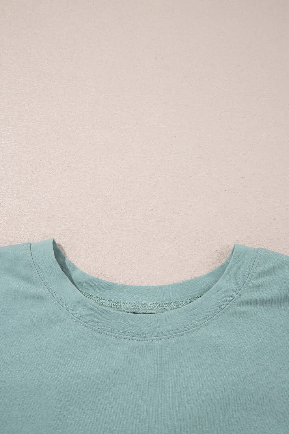Close-up of sage green Cosmic Crush Top neckline highlighting soft fabric and relaxed fit.