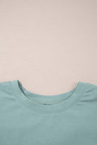 Close-up of sage green Cosmic Crush Top neckline highlighting soft fabric and relaxed fit.