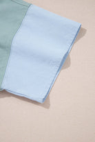 Close-up of the sleeve on the Cosmic Crush Top featuring sage green and sky blue colorblocked design.