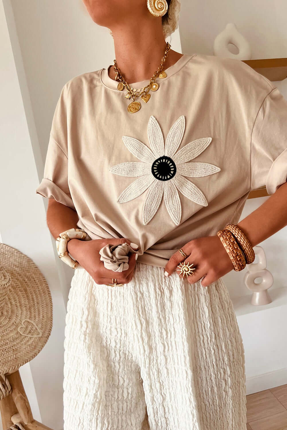 Model wearing Morning Daisy crochet floral graphic loose tee in beige with white textured pants.