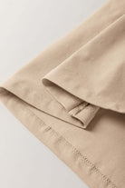 Close-up of a beige tee fabric showing relaxed drop shoulder and stitched hem details.