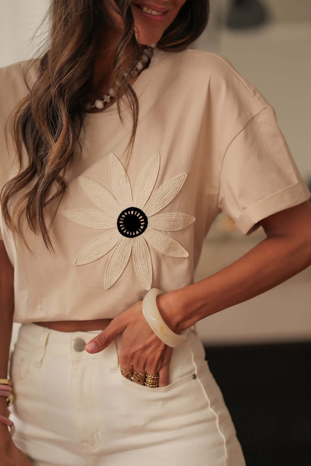 Woman wearing Morning Daisy top featuring crochet floral graphic and relaxed fit.