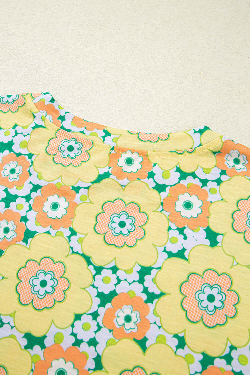 Close-up of Daisy Disco Top featuring vibrant yellow and orange flower print on a green background.