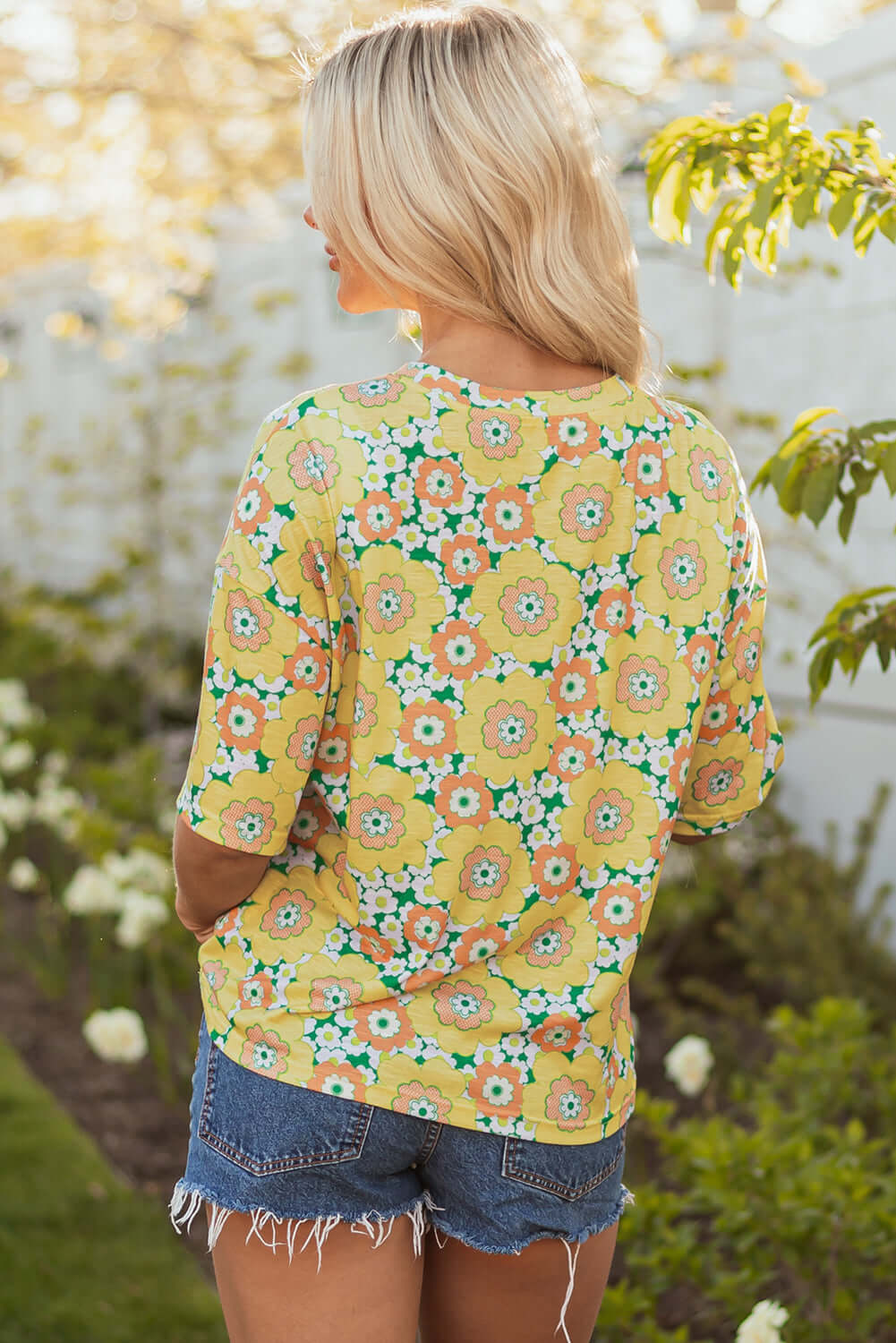 Yellow floral print Daisy Disco Top worn with denim shorts, perfect for summer days.