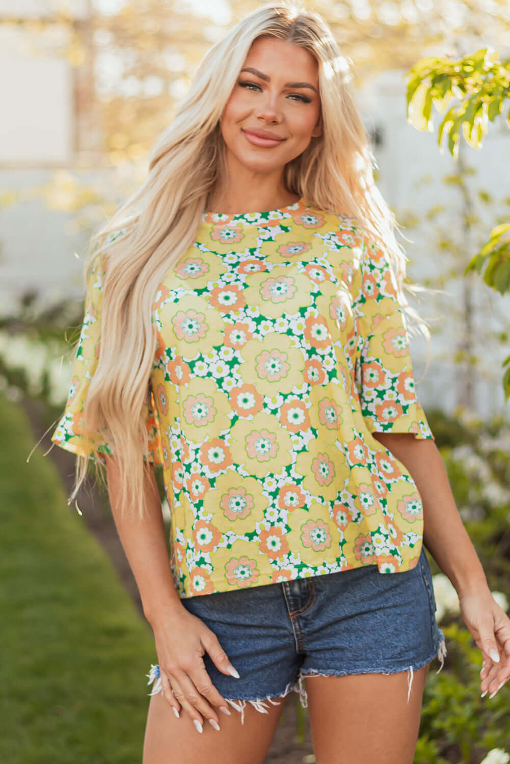 Daisy Disco Top in vibrant yellow floral print, styled with denim shorts for a chic summer look.