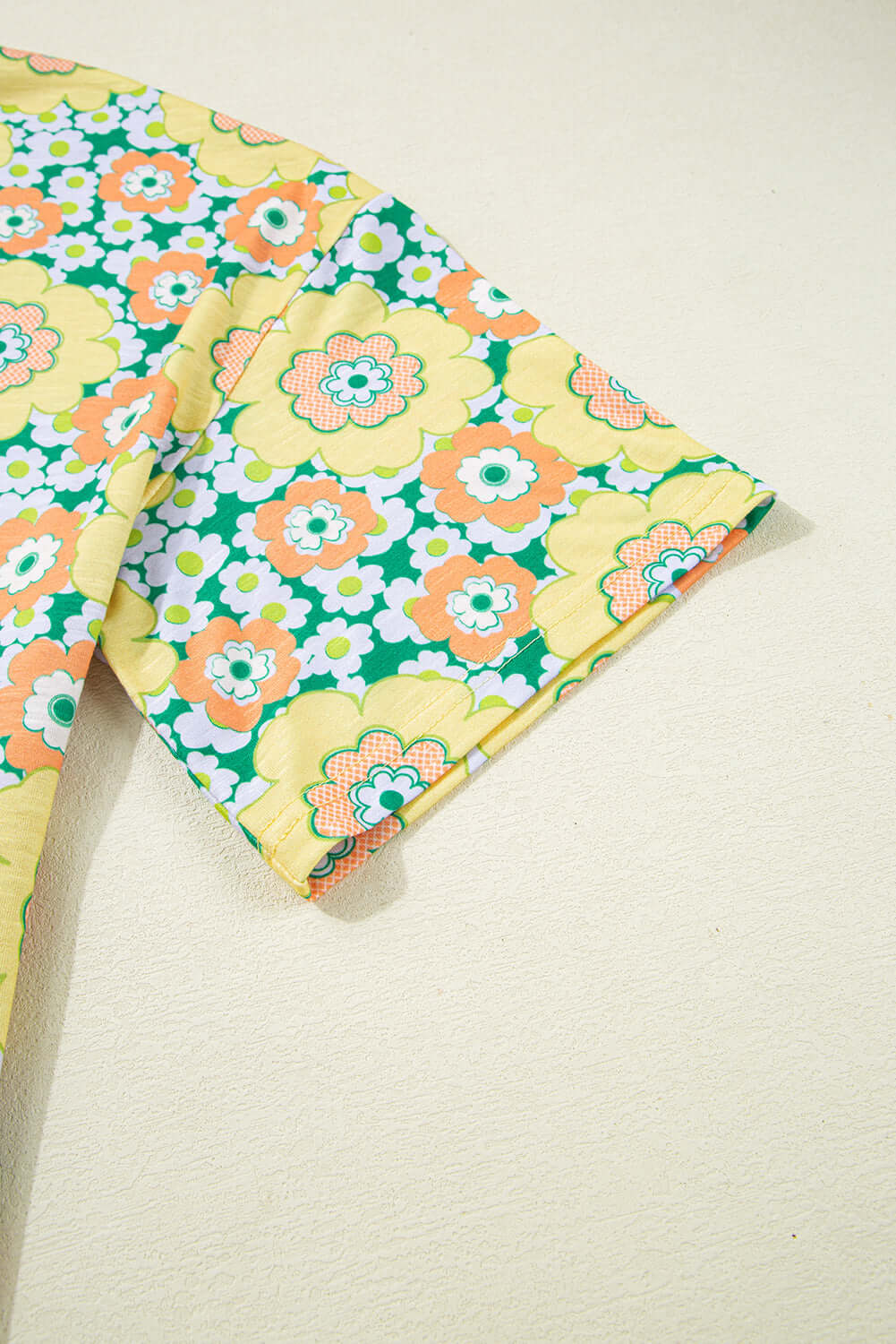 Detail of vibrant floral print on Daisy Disco Top showcasing yellow, green, and orange colors.