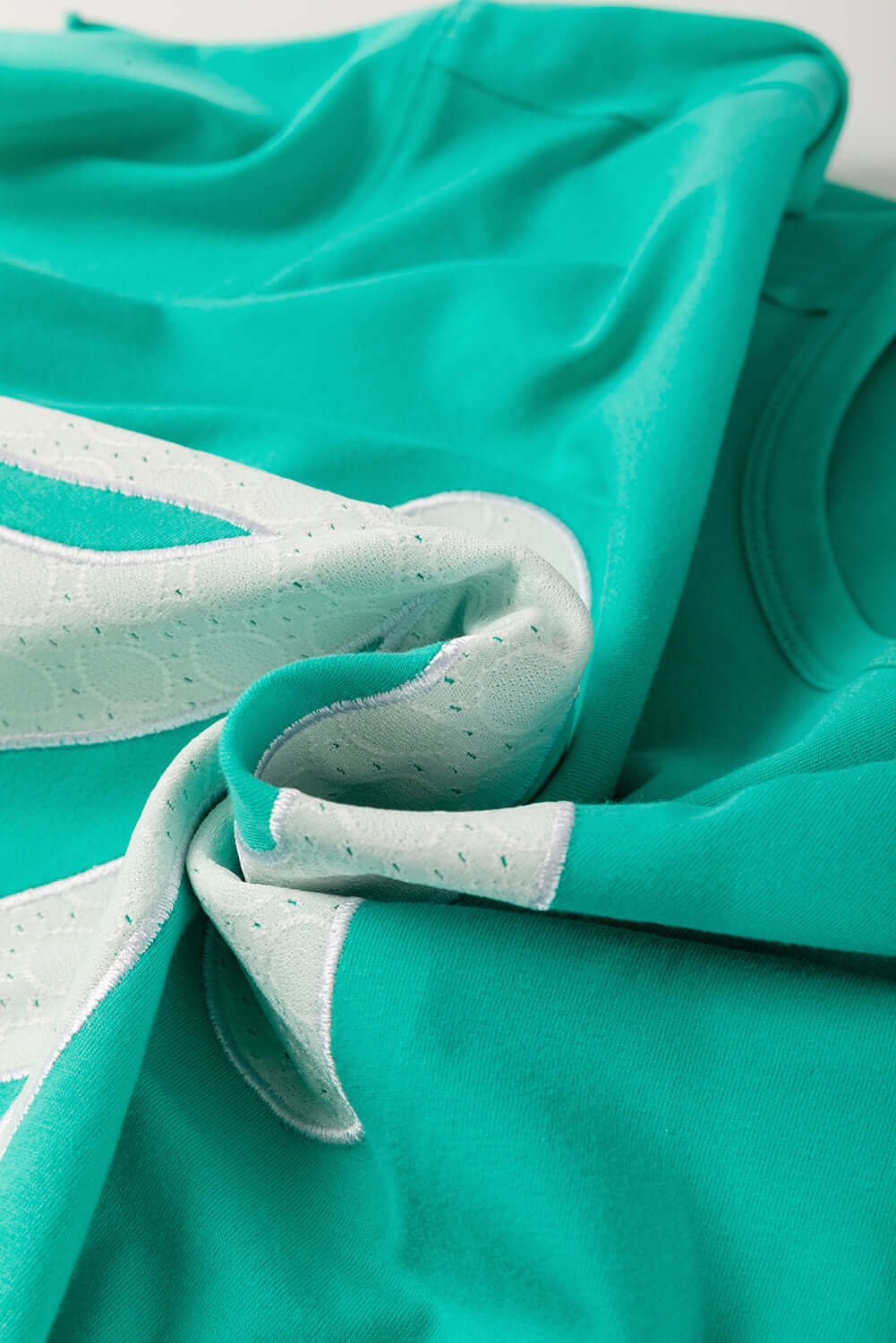 Teal lace bow detail on a raw edge tee, showcasing playful and stylish fashion elements.