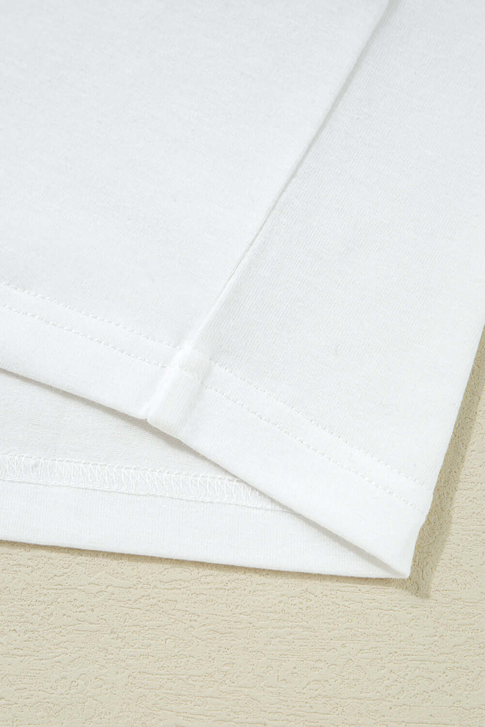 Close-up of the hem and sleeve detail of a Laced Logic Top, showcasing its minimalist white design.