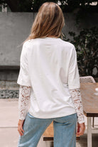 Back view of a woman wearing the Laced Logic Top with white lace long sleeves and casual denim jeans.
