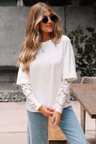 Woman in white Laced Logic Top with lace sleeves, wearing sunglasses, posing outdoors.