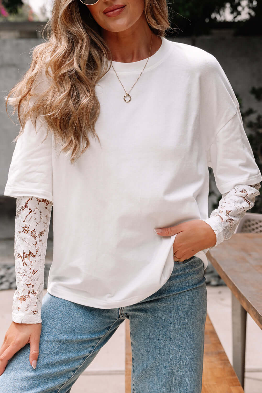 Model wearing Laced Logic Top, a white tee with lace long sleeves, styled casually with jeans and accessories.