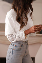 Model wearing the Laced Logic Top, a white lace long sleeve tee paired with light blue jeans.