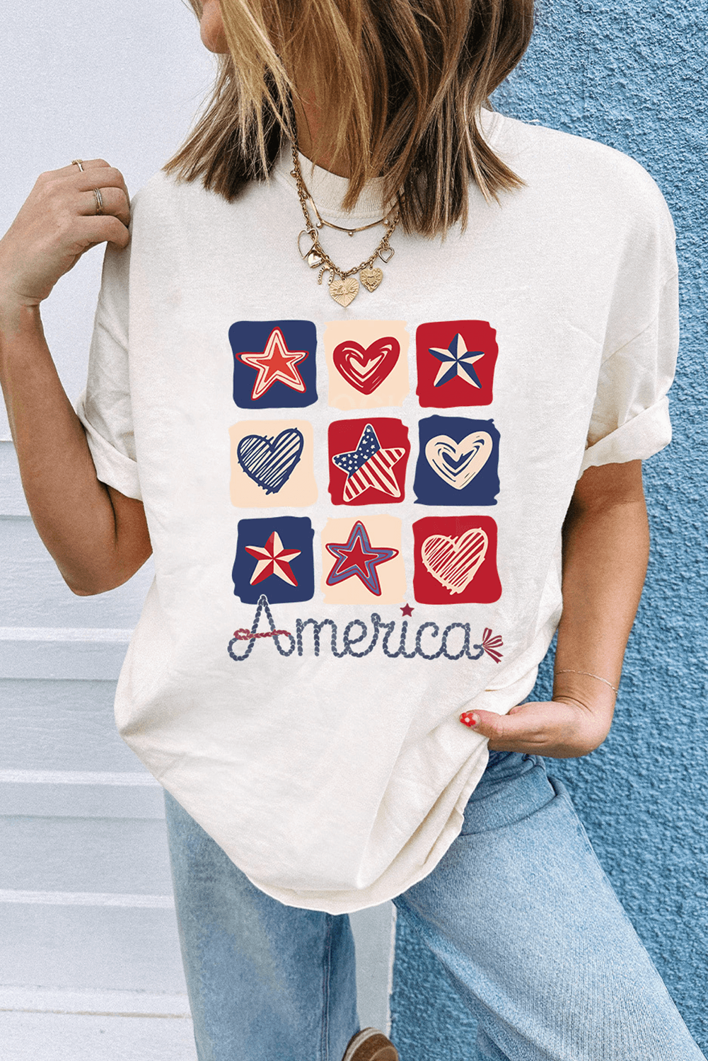 Woman wearing a white graphic tee featuring red, white, and blue hearts and stars with 'America' text.