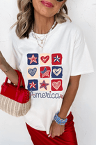 Woman wearing Land That I Love Tee with heart and star graphics, perfect for celebrating patriotic spirit.