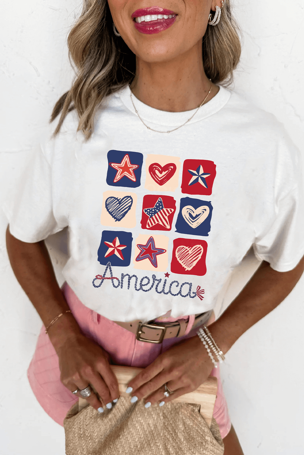 Woman wearing Land That I Love Tee with red, white, and blue heart and star graphics, celebrating patriotism.