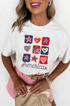 Woman wearing Land That I Love Tee with red, white, and blue heart and star graphics, celebrating patriotism.