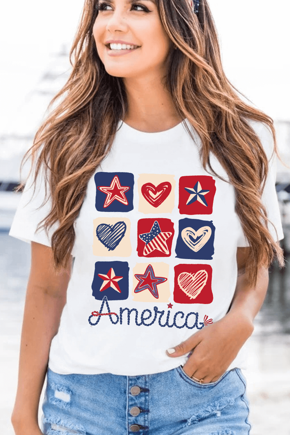 Woman wearing Land That I Love Tee featuring stars and hearts design, celebrating American patriotic spirit.