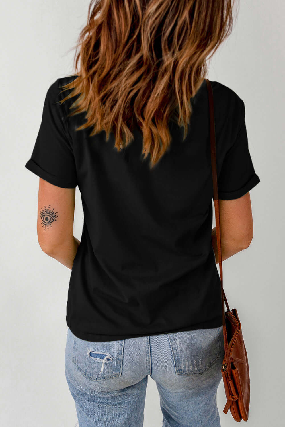 Back view of a woman wearing the HELLO FALL TEE in black, styled with casual jeans and a shoulder bag.