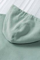 Close-up of green fleece-lined hoodie fabric with hood from Vivian-Lu, showcasing soft material and stitching details.