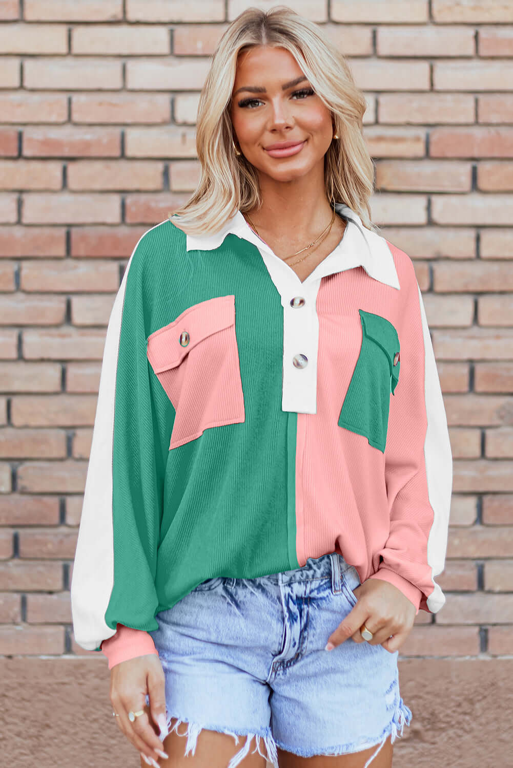 Woman wearing Bold Boundaries Top with buttoned neckline and color block pattern in pink and green, paired with denim shorts.