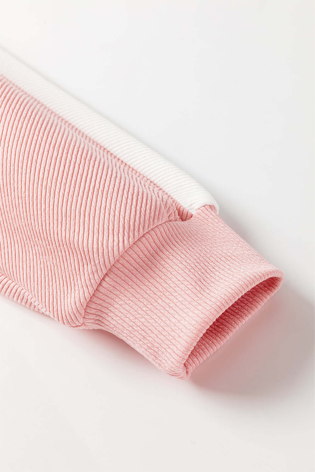 Close-up of pink and white color block sleeve from BOLD BOUNDARIES TOP by Vivian-Lu, showcasing the ribbed texture and relaxed fit.