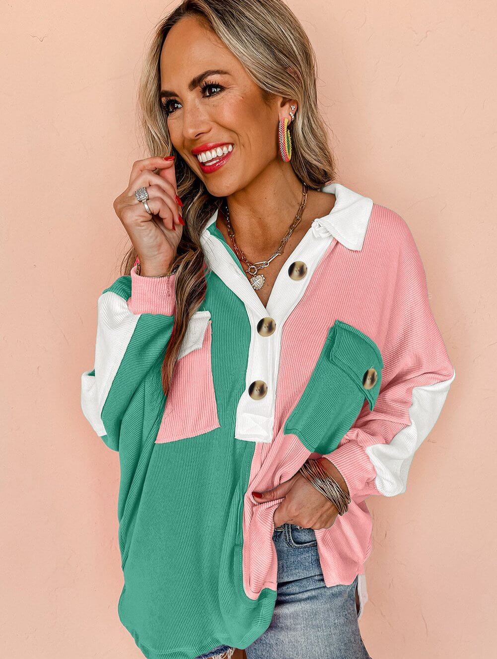 Woman wearing a color block top with a buttoned neckline, featuring green, pink, and white sections, styled with casual jeans.