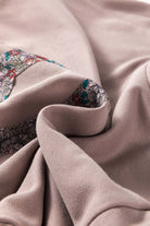 Close-up of a soft beige sweatshirt with a colorful floral pattern, showcasing its smooth fabric and intricate design details.