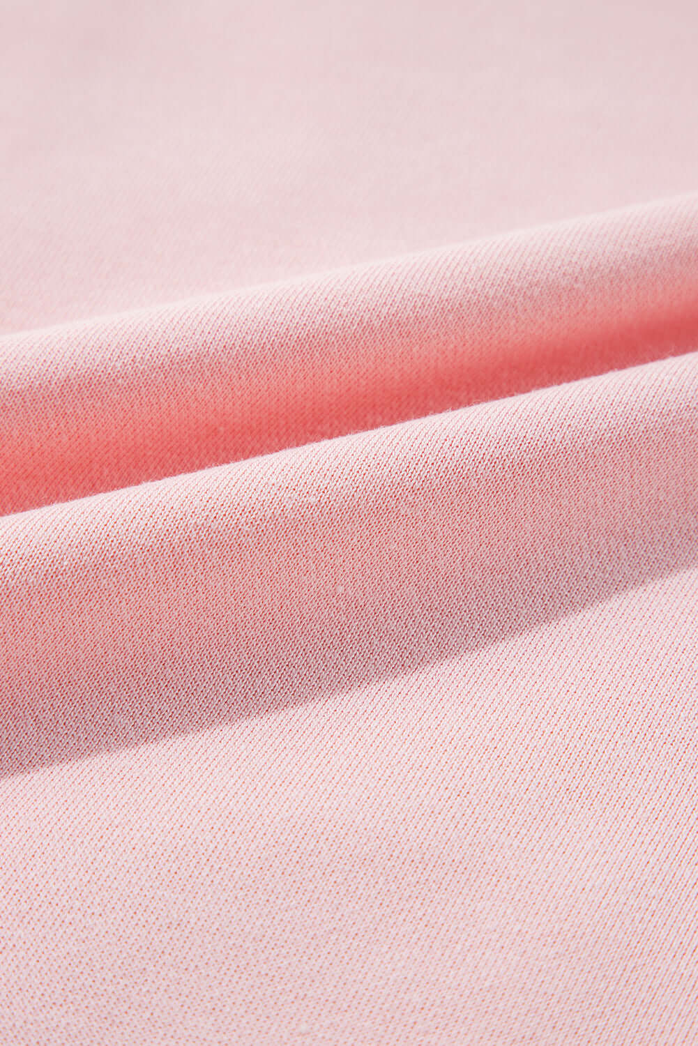 Close-up of light pink fabric texture from PUT A BOW ON IT Top by Vivian-Lu, highlighting soft material and ribbed design.