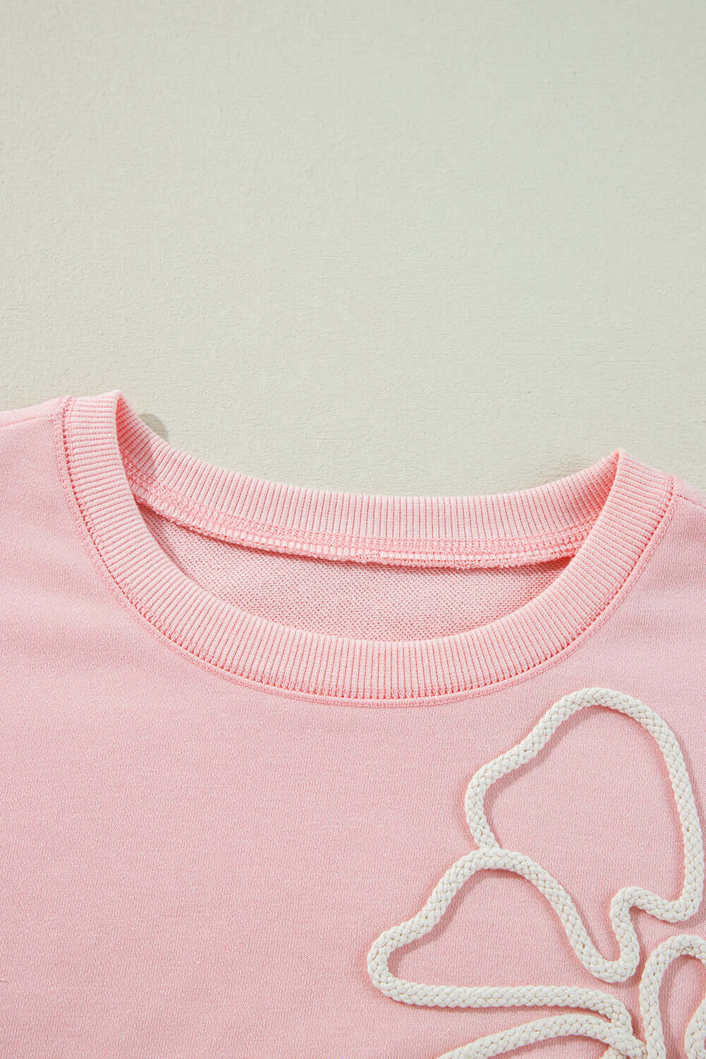 Light pink sweatshirt with off white bow embroidery and ribbed collar, Vivian-Lu's PUT A BOW ON IT Top, close-up view.