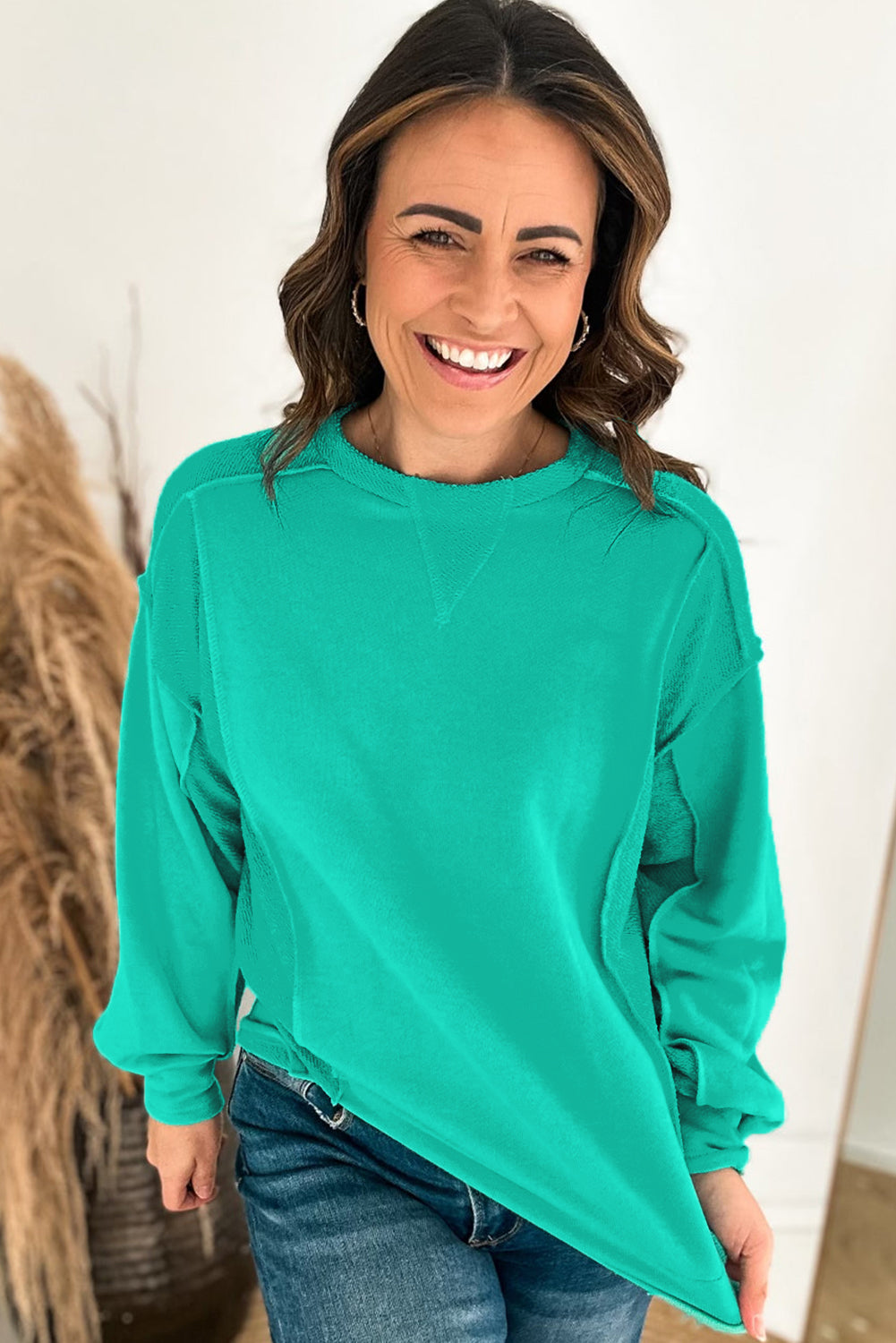 Cheerful woman in teal We Meet Again Crewneck sweatshirt, showcasing relaxed fit and stylish design.