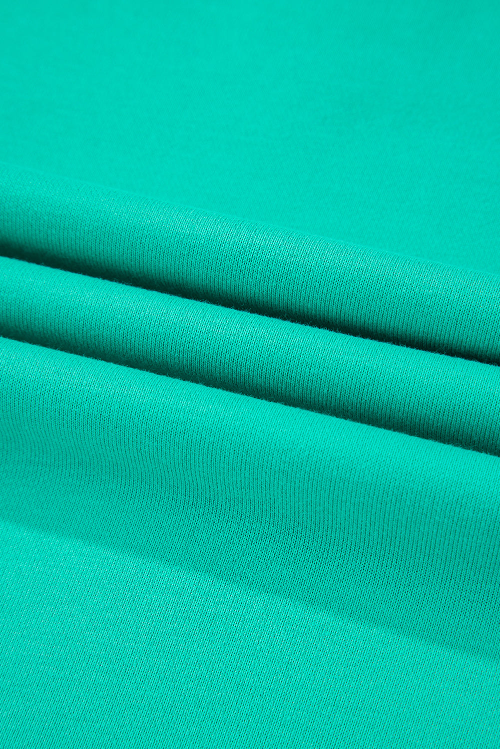 Close-up of soft teal fabric showcasing smooth texture, perfect for casual stylish wear.