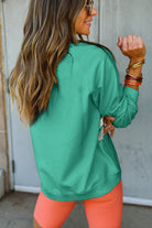 Woman wearing aqua crewneck pullover with rainbow color-block, paired with orange leggings, showcasing casual fashion style.